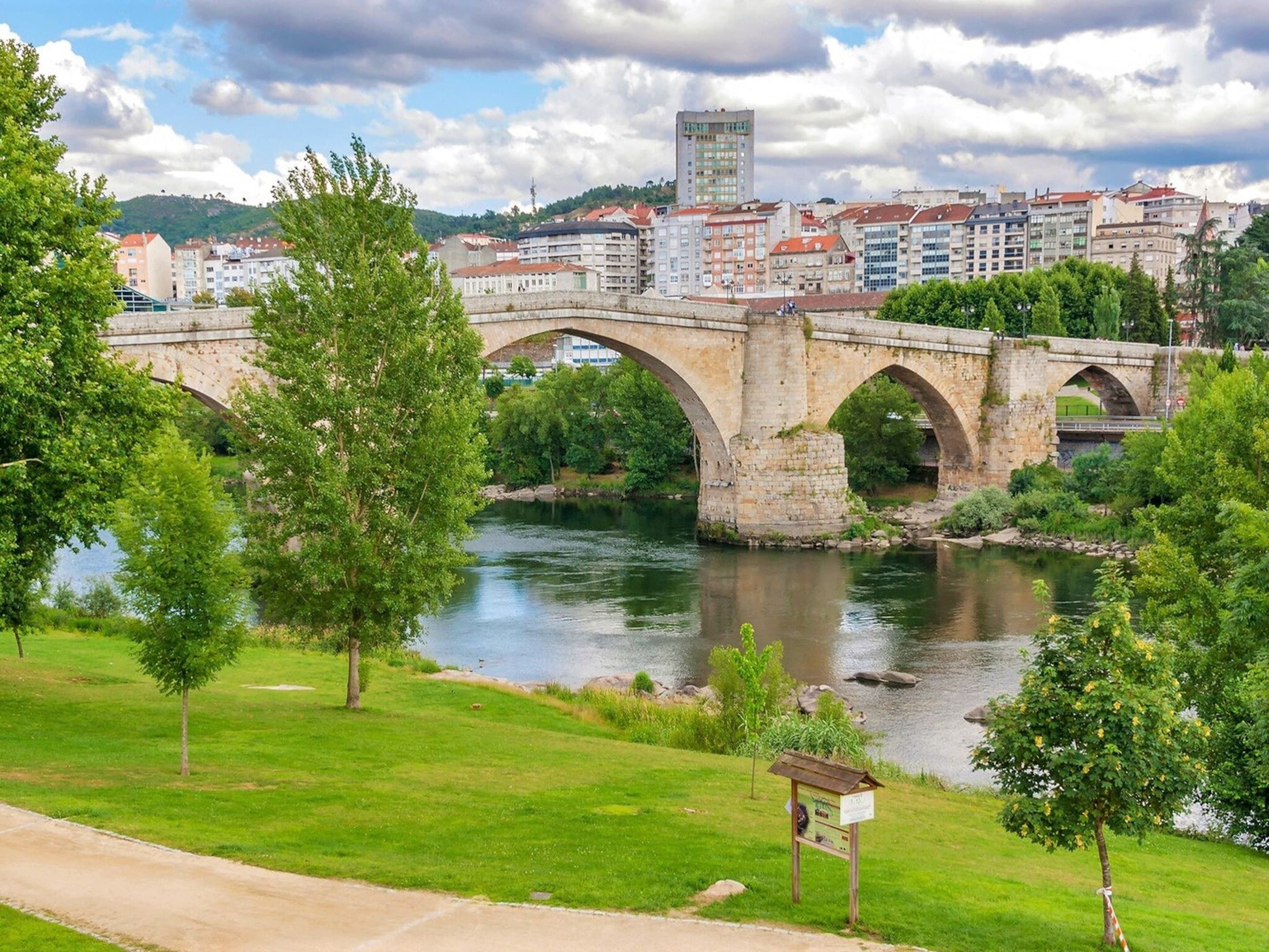 A stone bridge over a river with a cityscape in the background.