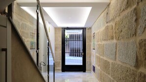 A hallway with a stone wall, a glass railing, and a black door with metal bars. - Belvilla by OYO Villa Trabazos Abellas (Ourense)