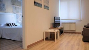 A hotel room with a bed, a TV, a small table, and a window with blinds. - Belvilla by OYO Villa Trabazos Abellas (Ourense)