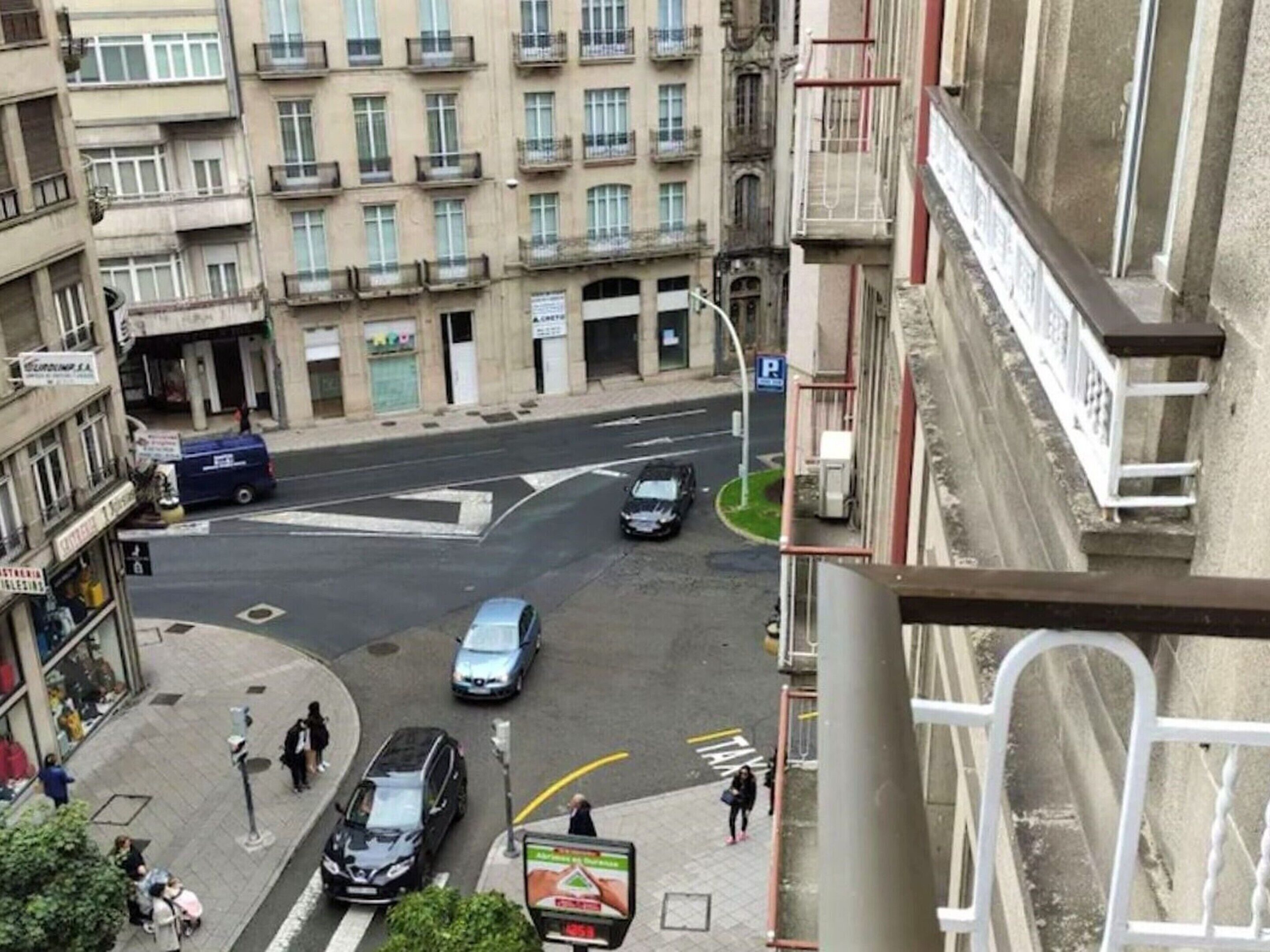 Straßenansicht eines Gebäudes mit Balkonen und einer Fußgängerampel.