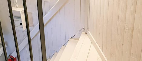 Una escalera con paredes blancas y barandilla de metal.