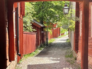 A narrow cobblestone alley flanked by red wooden buildings with a street lamp overhead. - 4 Person Holiday Home in Nykil (Nykil)