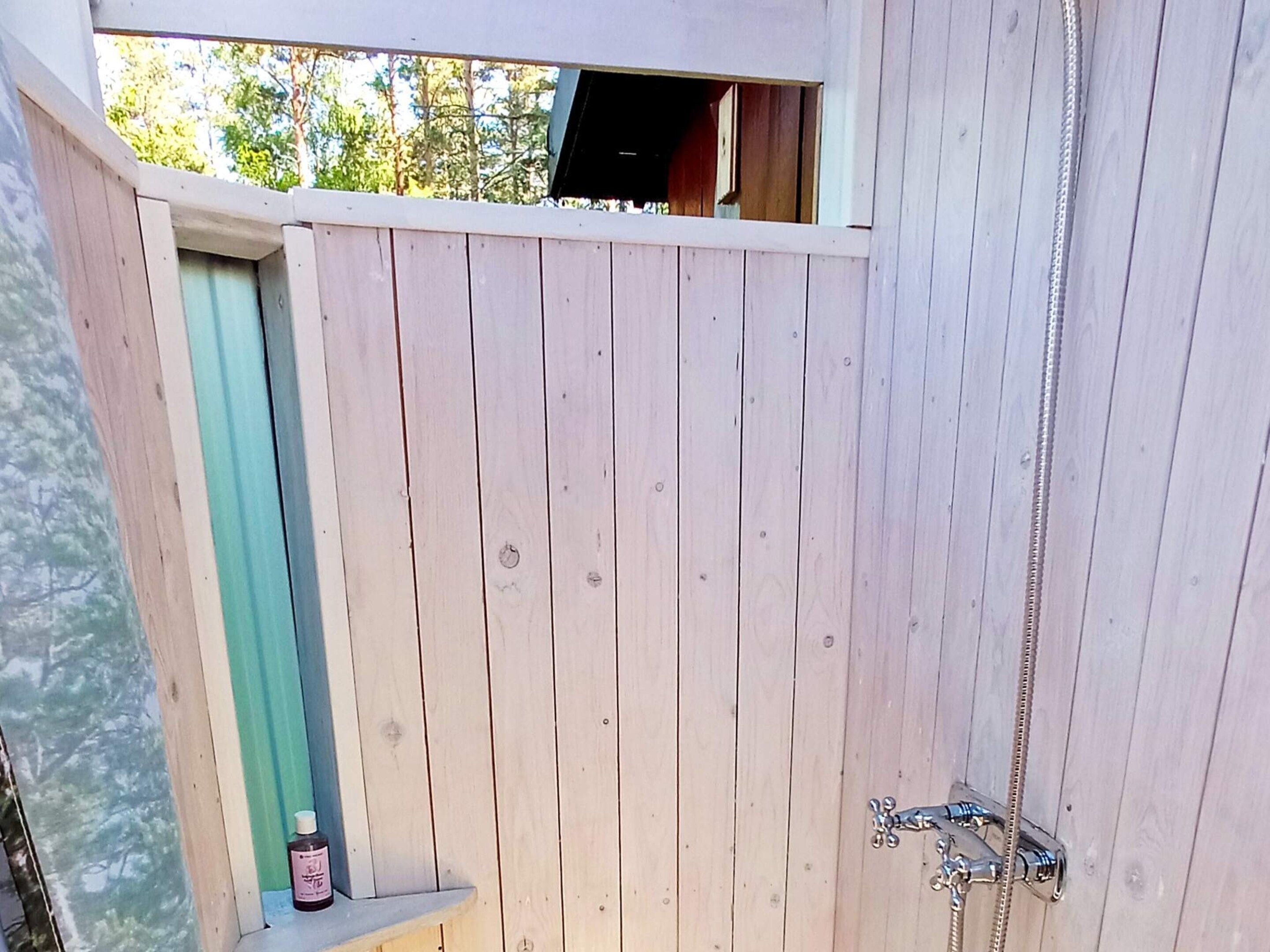 A wooden gate with a zipper, a small shelf with a bottle, and a window above the gate.