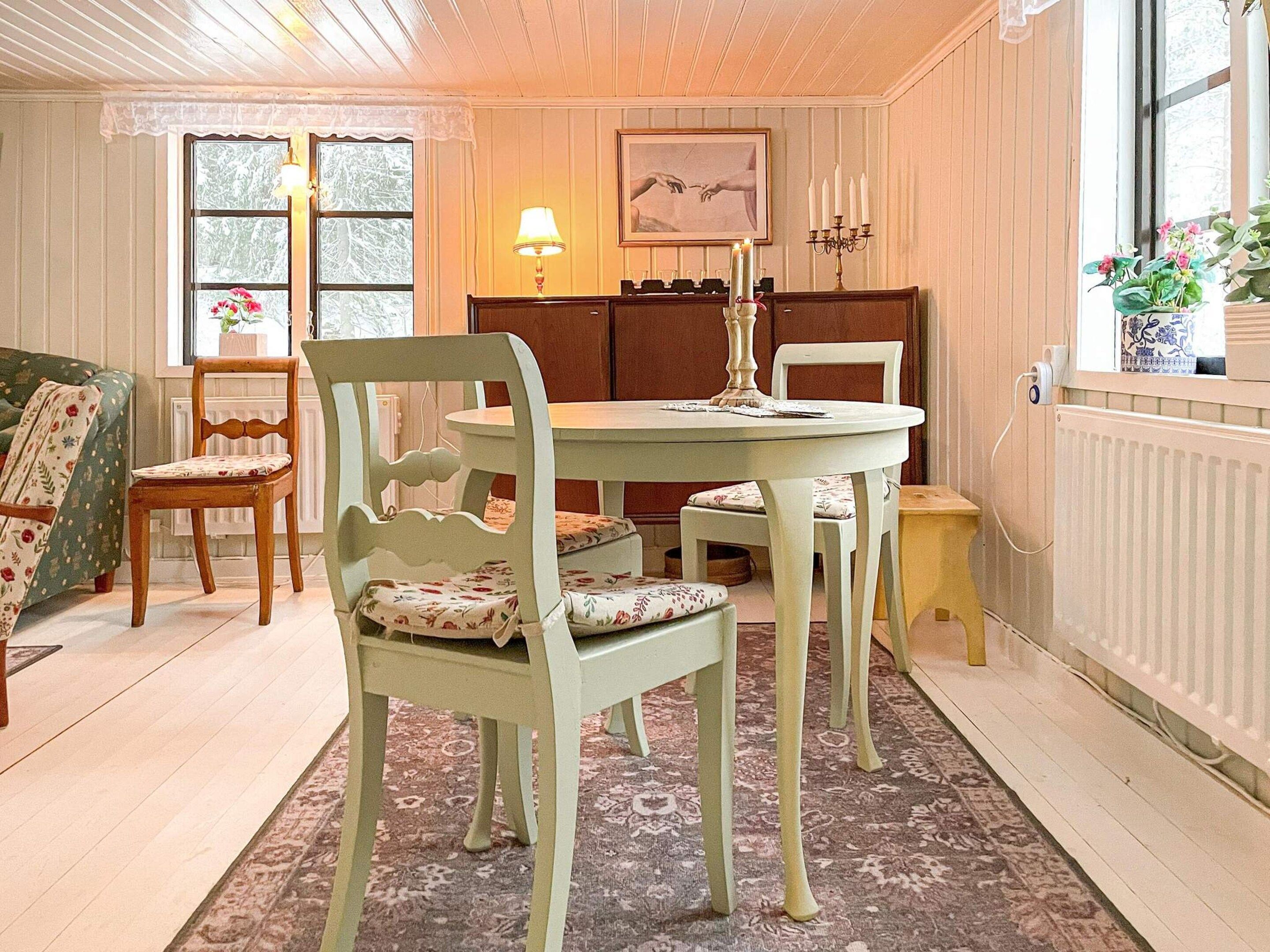 Un coin repas comprenant une table ronde, deux chaises, un radiateur et une fenêtre donnant sur un paysage agréable.