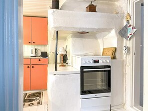Una cocina compacta con un horno blanco, una pequeña encimera y un solo armario naranja.