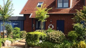 Une maison en briques rouges, avec un toit en tuiles, une petite fenêtre et une porte.