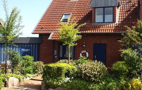 Une maison en briques rouges, avec un toit en tuiles, une petite fenêtre et une porte.