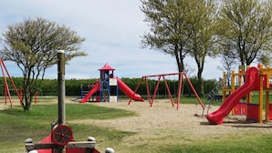 Une aire de jeux avec des balançoires, des toboggans et une structure d’escalade.