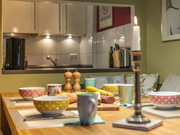 Una cocina con armarios blancos, una vela encendida y distintos utensilios de cocina sobre la encimera.