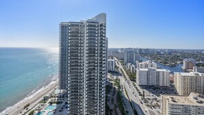 A high-rise hotel with multiple floors, a pool area, and a view of the coastline.