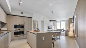 A modern kitchen with built-in appliances, a central island, and a dining area with a view.