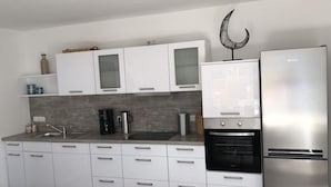 Eine moderne Küche mit weißen Schränken, einem Edelstahlkühlschrank und einem eingebauten Backofen.