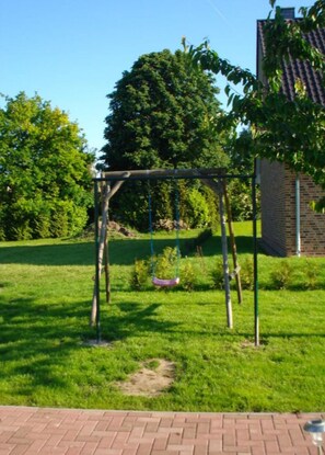 Enjoy a family-friendly atmosphere in our serene outdoor space with a swing set surrounded by lush greenery.