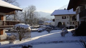 A snow-covered courtyard with buildings, including a hotel named "Haus Ostara," and a mountain backdrop. - Holiday Apartment Alpenstern (Ruhpolding)