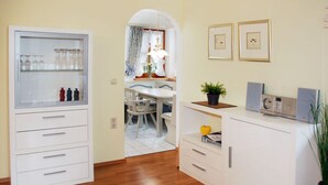 A kitchen with white cabinets, a wooden floor, and a dining area with a table and chairs. - Holiday Apartment Alpenstern (Ruhpolding)