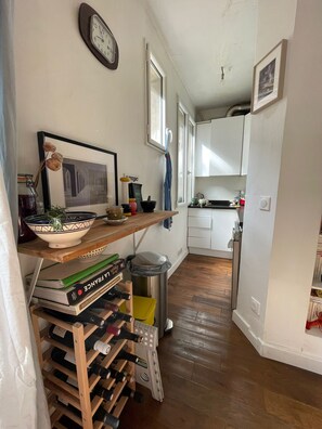 Compact kitchen area with wine rack, trash bin, and shelf for kitchen essentials.