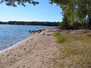 A sandy beach with a rocky shoreline and trees. - 5 Star Holiday Home in Ljustero (Ljusterö)