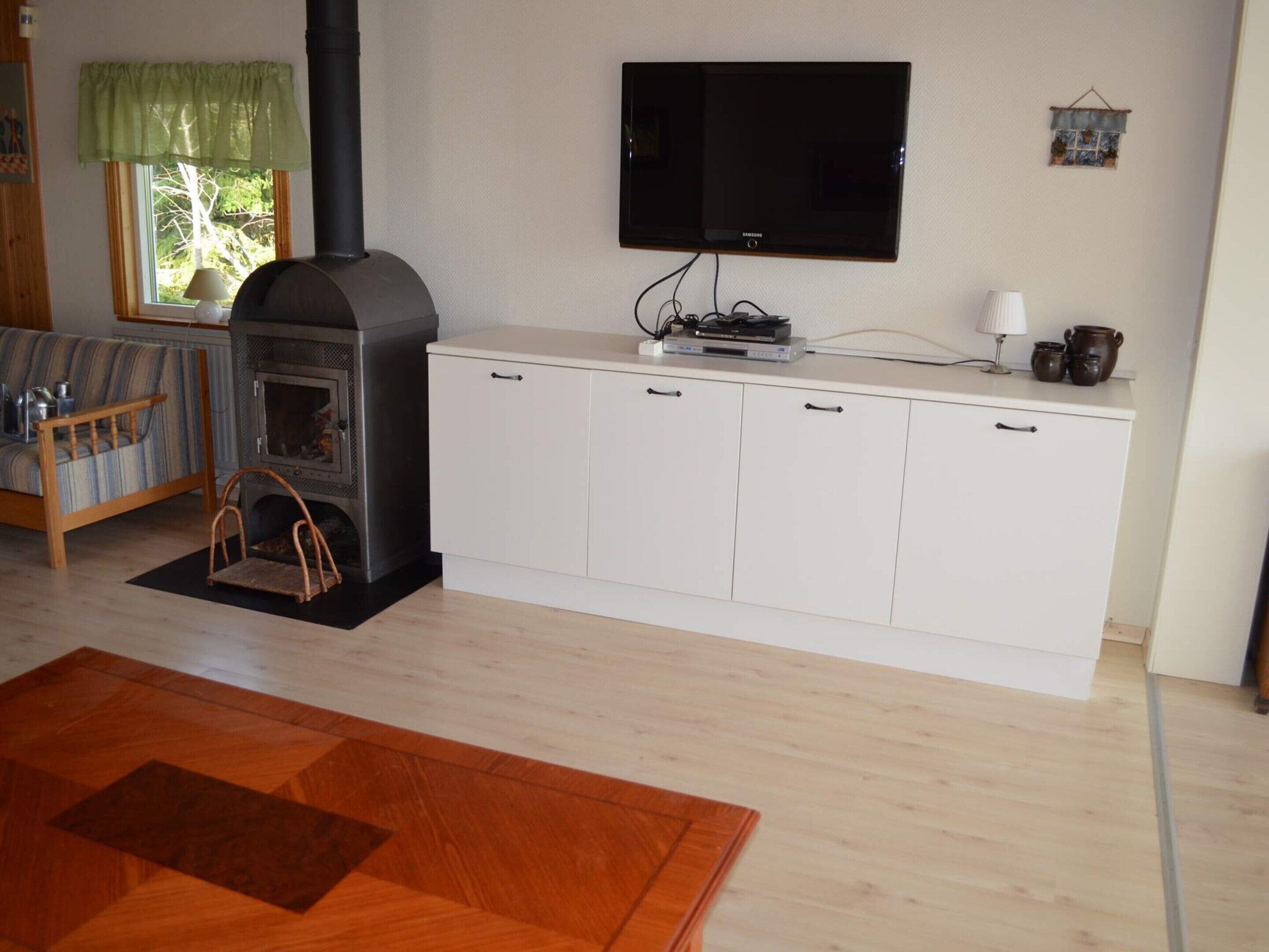 A living room with a fireplace, a television, and a white cabinet.