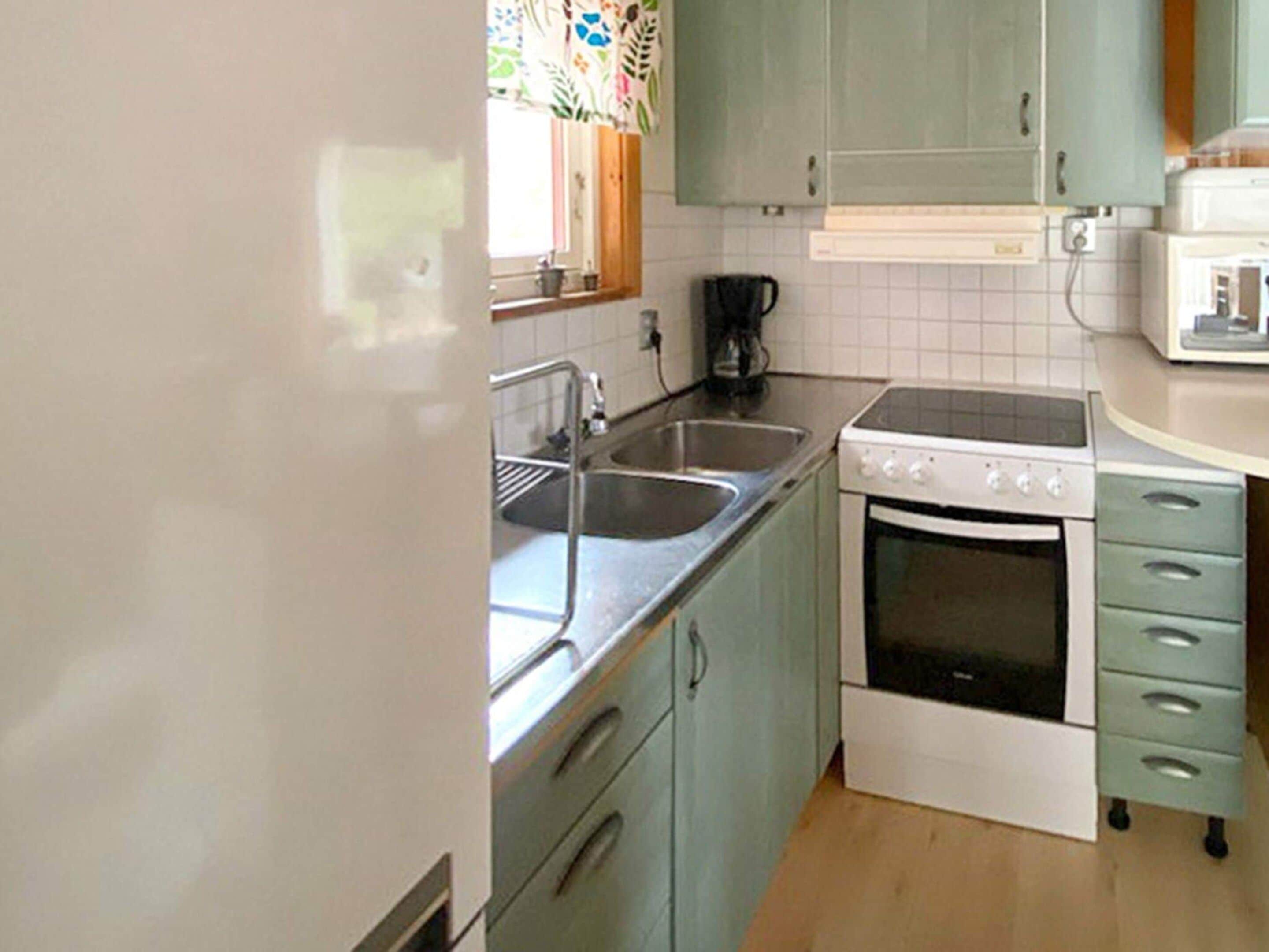 A compact kitchen with a sink, stove, and a microwave.