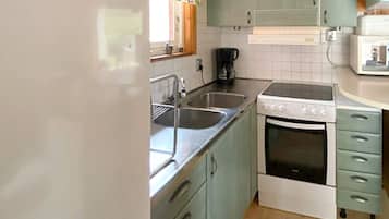 A compact kitchen with a sink, stove, and a microwave.