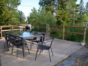 A wooden deck with a glass-top table and chairs, surrounded by a wooden railing and lush greenery. - 5 Star Holiday Home in Ljustero (Ljusterö)