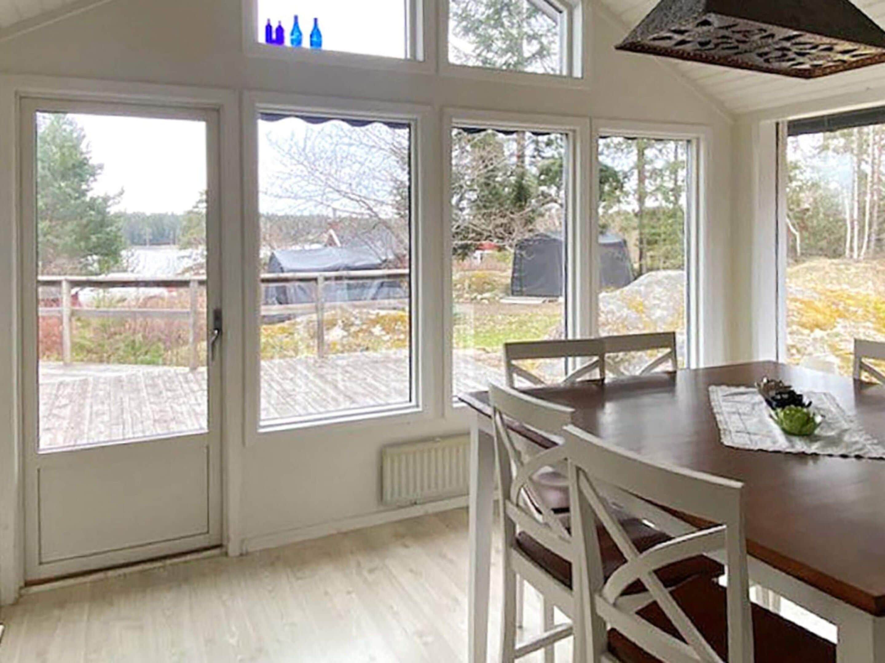 Un comedor con mesa y sillas, ventanas amplias con vistas al exterior y un techo con un diseño decorativo.