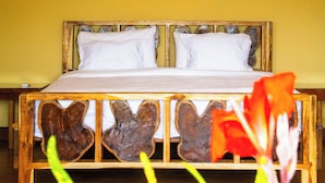Un lit avec une tête de lit en bois, une literie blanche et un climatiseur fixé au mur au-dessus.