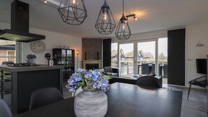 A modern kitchen with a central island, pendant lighting, and a view of the outside.