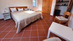 Une chambre à coucher avec un lit, des tables de chevet, une armoire en bois, une chaise et une petite table.