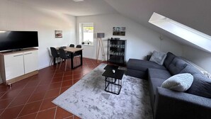 Un salon moderne doté d’un téléviseur à écran plat, d’une table à manger, d’un canapé et d’une petite table basse.