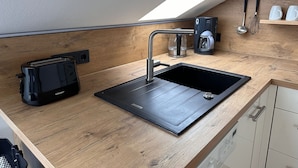 Une cuisine moderne équipée d’un évier intégré, d’une machine à café et d’un grille-pain.