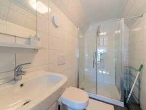 A modern bathroom with a white sink, toilet, and glass-enclosed shower.