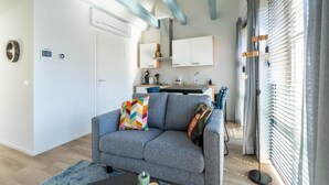 A modern living room with a grey sofa, a coffee table, and a kitchen area in the background. - Modern Apartments in the Heart of Sneek (Sneek)