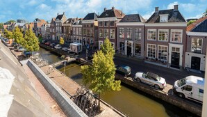 A canal-side street with traditional European buildings, a bridge, and parked cars. - Modern Apartments in the Heart of Sneek (Sneek)