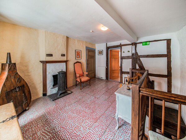 A room with a fireplace, a wooden chair, a small table, and a staircase.