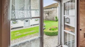 Una habitación con un amplio ventanal que da a un patio con pared de piedra, césped y un pequeño jardín.