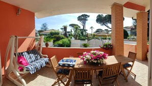 Une terrasse avec un fauteuil suspendu, une table à manger avec des chaises et une vue sur le quartier.