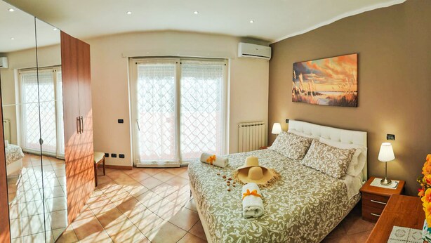 Une chambre à coucher avec un lit, une table de chevet, une lampe, un tableau et une vue sur l’extérieur.