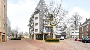 A modern apartment building with a prominent triangular design, multiple balconies, and a paved courtyard. - Apartment in Nieuwpoort With Beach Access (Nieuwpoort)