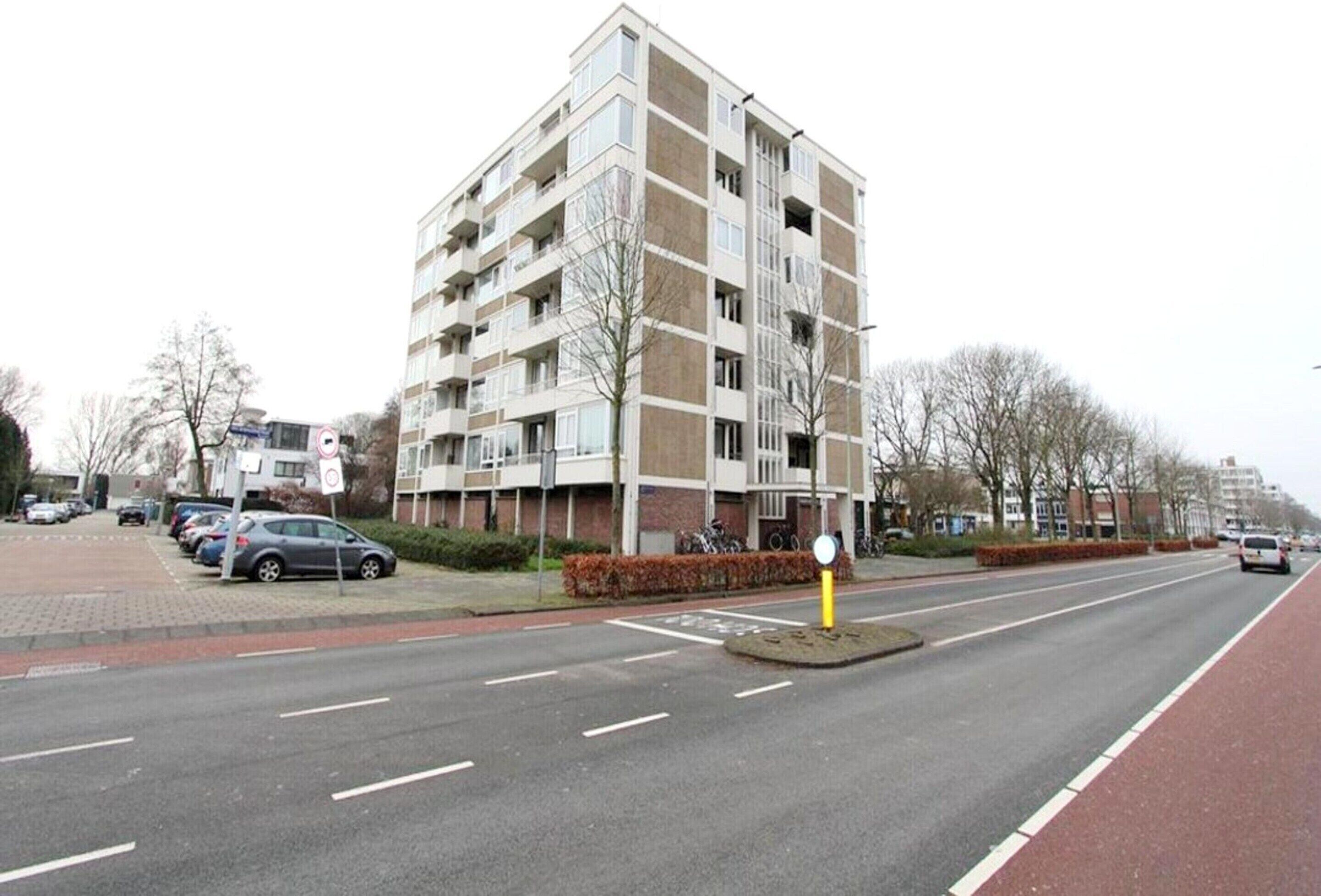 A multi-story residential building with a parking lot in front.
