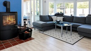 A cozy living room with a wood-burning stove, grey sofa, and a glass coffee table. - 12 Person Holiday Home in Hadsund-by Traum (Hadsund)