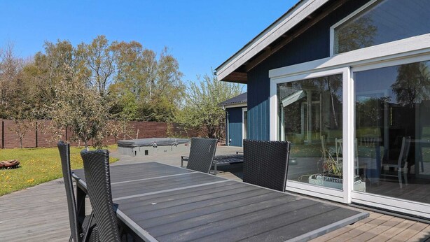 A deck with a table and chairs, a hot tub, and a glass door leading to a covered area. - 12 Person Holiday Home in Hadsund-by Traum (Hadsund)