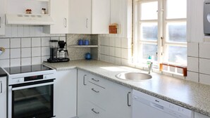 A kitchen with white cabinets, a built-in oven, a dishwasher, and a window with a view. - 12 Person Holiday Home in Hadsund-by Traum (Hadsund)