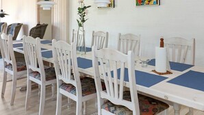 A dining area with a long table, white chairs, and blue placemats. - 12 Person Holiday Home in Hadsund-by Traum (Hadsund)