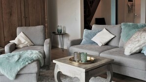 A living room with two grey sofas, a wooden coffee table, and a small side table with decorative items. - See.eck Timmel Modern Retreat (Grosefehn)