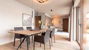 Un comedor moderno con una mesa y sillas de madera, un jarrón con flores y un cuadro en la pared.