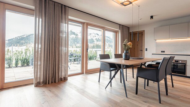 Una cocina moderna con horno empotrado y comedor con mesa y sillas de madera.