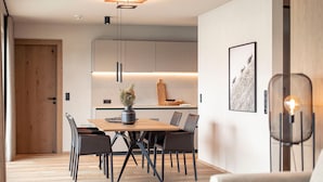Un comedor moderno con una mesa y sillas de madera, un jarrón con flores e iluminación colgante.