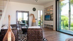A modern living room with wicker furniture, a large mirror, and a television. - Villa in Salobre Golf With Private Pool (San Bartolomé de Tirajana)