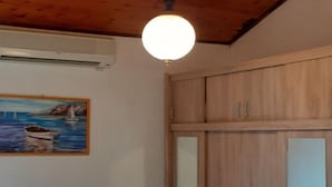 A room with wooden cabinets, a painting of a boat on water, and an air conditioning unit. - Apartments Rudi - One Bedroom Apartment With Terrace (Novi Vinodolski)